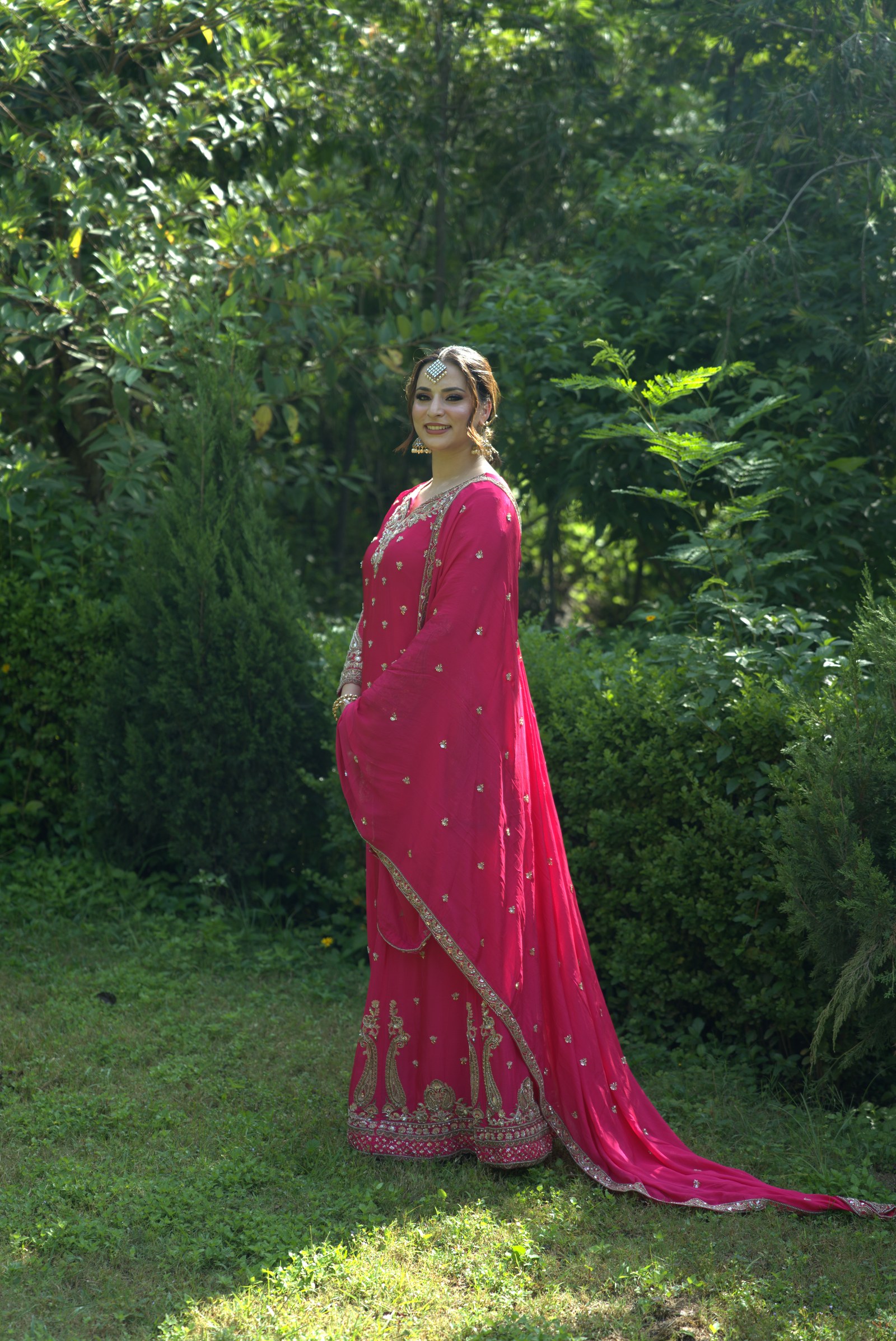 Full-length fuchsia suit outdoors with a long bordered dupatta and wide-legged trousers