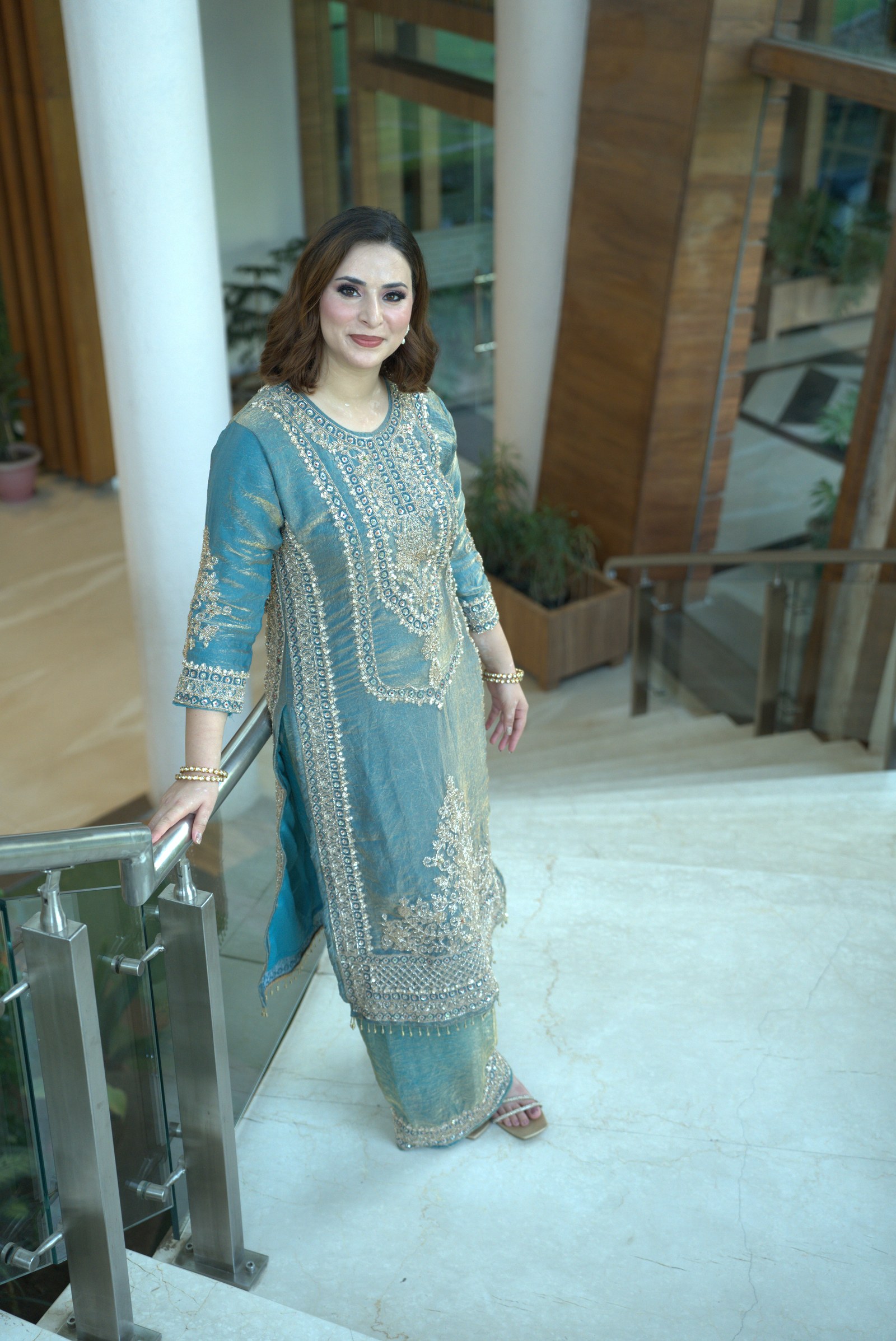 Soft blue embroidered suit standing beside a staircase